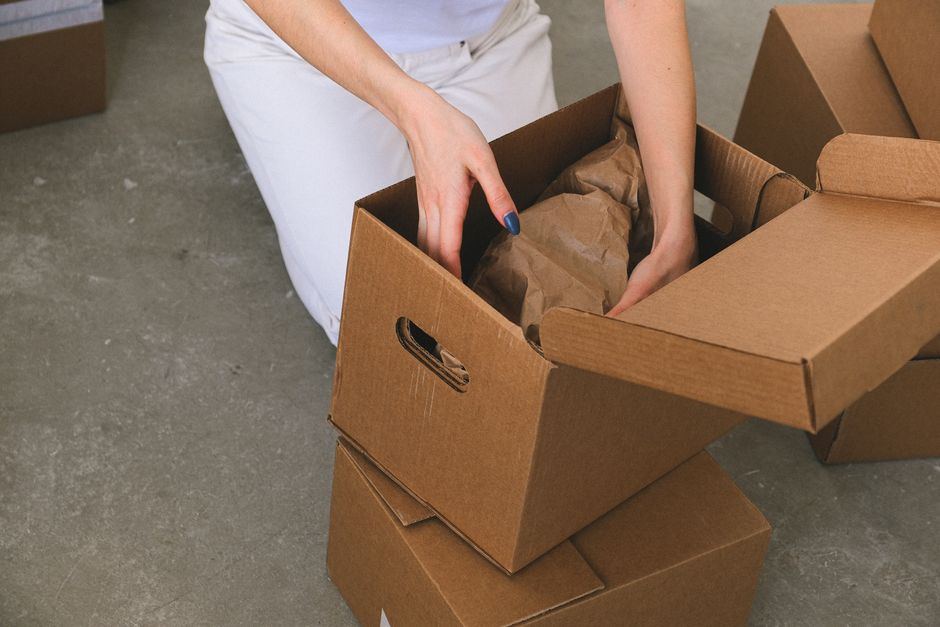 A person packing clothing into a cardboard box